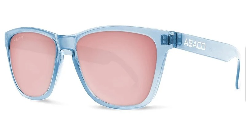 Studio product photograph of light blue translucent sunglasses with pink lenses, three-quarter view